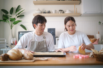 Happy couple baking cookies together in a bright, modern kitchen. They enjoy quality time making homemade treats with love.