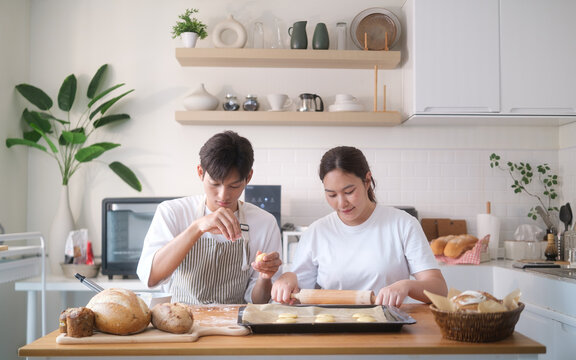 Asian couple baking together in a modern kitchen, preparing dough and having fun. - Powered by Adobe