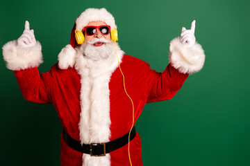 Santa in red suit with yellow headphones dances against a green backdrop for Christmas fun and holiday energy