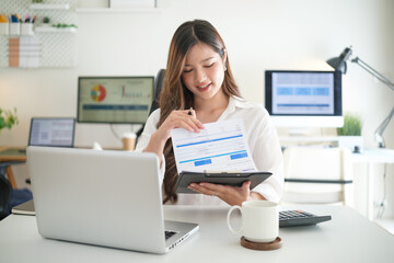 Young businesswoman reviews financial documents during remote work at home office.