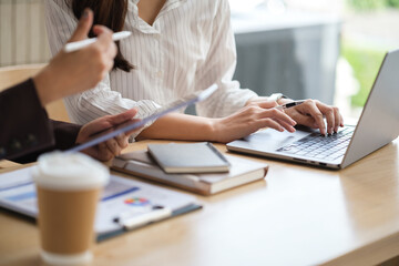 Close-up of hands working on laptop and tablet during a business discussion at a modern desk.