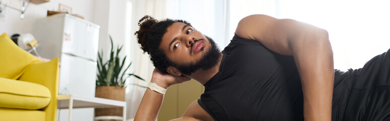 Fototapeta premium Home workout session for an athletic African American man with curly hair and beard