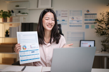 Smiling woman shows business charts during a video conference call from home office.