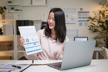 Cheerful woman presenting data analysis report at her desk in modern office.