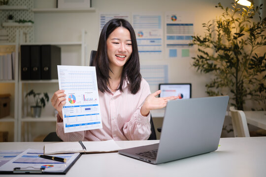 Happy woman presenting a colorful business report during an online meeting from a home office. - Powered by Adobe