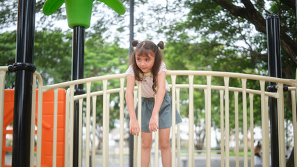 Obraz premium Young girl leaning over playground railing with a curious expression.