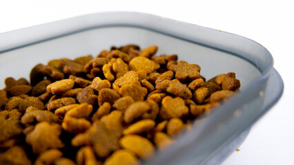 Dry pet food close up, cat kibble pile in gray plastic bowl isolated on white background