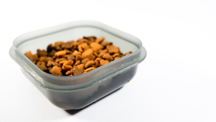 Dry pet food close up, cat kibble pile in gray plastic bowl isolated on white background