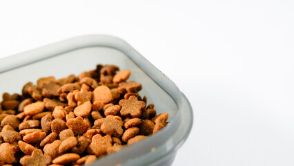 Dry pet food close up, cat kibble pile in gray plastic bowl isolated on white background