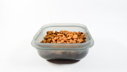 Dry pet food close up, cat kibble pile in gray plastic bowl isolated on white background