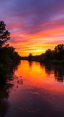Vibrant sunset paints the sky over tranquil river landscape.