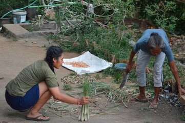 The mother tidies the wooden cutting board used for lemongrass while her daughter collects cleaned...