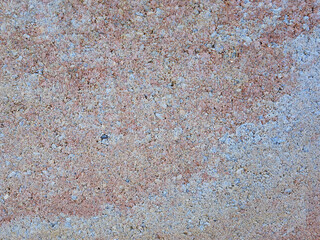 Close up eroded stucco showing horizontal red band and granular surface textures