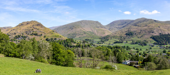 panoramic view of grasmere village from silver howe with helm crag on the left and seat sandal fairfield and stone arthur centre to right sunny spring day no people