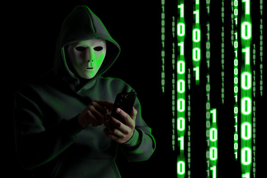 Cyber attack. Hacker in mask using mobile phone on black background. Green glowing binary code near him
