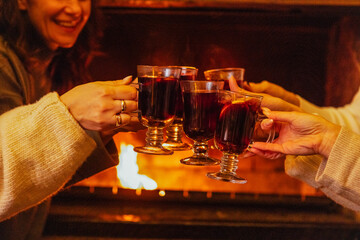 Close-up of the women saying a toast and clinking glasses with mulled wine. Cups of spicy hot...
