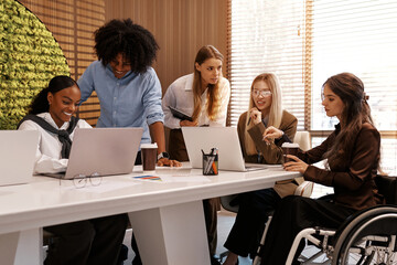 Inclusive diverse business team meeting with woman using wheelchair at modern office