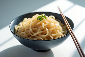 A simple bowl of delicious Asian noodles with chopsticks in bright sunlight