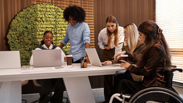 Inclusive diverse business team meeting with woman using wheelchair at modern office