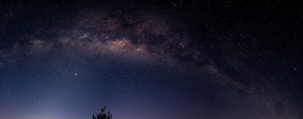 A panoramic, ultra-wide view of the Milky Way band stretching across a dark, star-filled night sky.