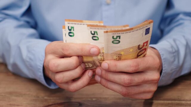 Close-up of male hands counting euro banknotes. Man in blue shirt counting money, European currency. Financial concept background for salary, savings or budget planning. Investor counting money.