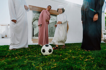 Arab family playing soccer together outdoors