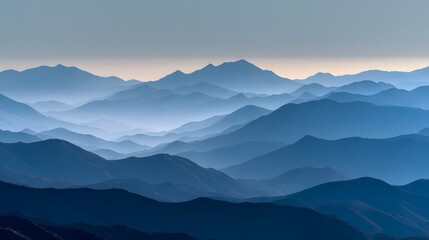 Successive layers of mountainous terrain fade into a pale sky creating a misty blue vista