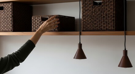 Hand reaching for storage box on wooden shelf.