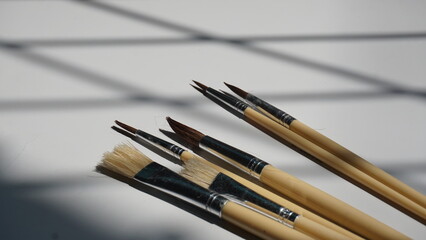 Fototapeta premium Paint brushes on a white background with shadows from the window