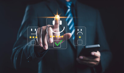 Businessman using smartphone and touching virtual happy face icon with five star rating, symbolizing positive customer feedback, online review, and satisfaction evaluation concept.