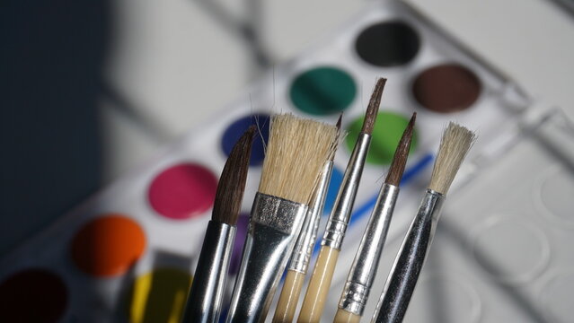 Paint brushes and watercolor paints on a white background close up