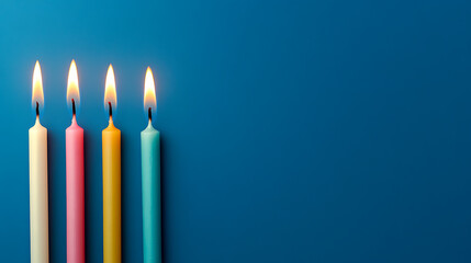 Four colorful candles stand tall, flames flickering against a serene blue background. Warm light meets cool tones in this minimalist composition, a symphony of colors and light.