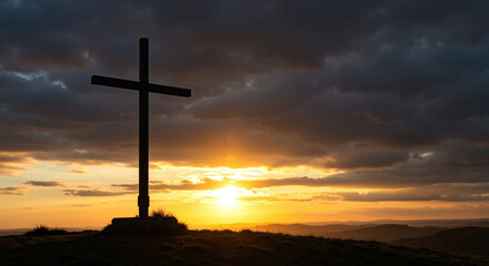 Silhouette of Christian cross on hill at sunset. Dramatic sky over mountain landscape. Faith and religion concept