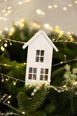 Wooden house ornament with warm lights and fir branches