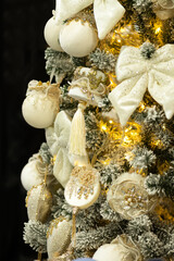 Golden and white Christmas ornaments on decorated tree with lights