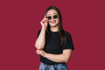 Obraz premium vibrant studio shot capturing playful woman dressed casually with accessories against rich red