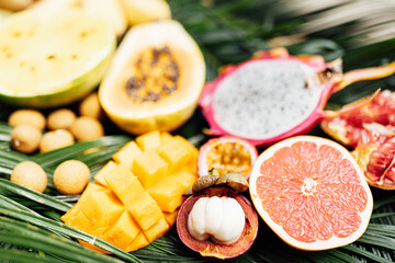 Fresh exotic fruits on green tropical palm leaves background - papaya, mango, pineapple, passion fruit, dragon fruit, watermelon. flat lay, overhead. Healthy food and diet concept. Top view.