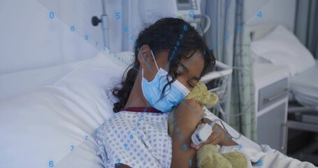 Child patient resting in hospital bed with gown, surgical mask, teddy bear, pulse oximeter