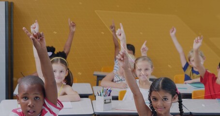 Raising hands, two front-row students answering question in elementary classroom with pencils