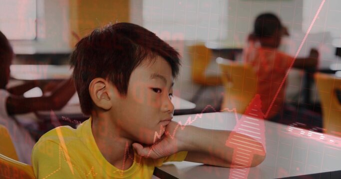 Gazing Asian boy leaning chin on hand in brightly lit classroom, with desks yellow chairs windows