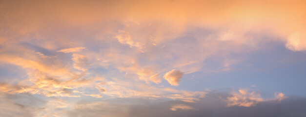 romantic sunset sky scenery orange lighted clouds against blue background, pastel colors
