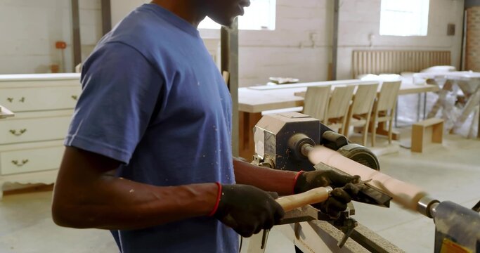 Turning mid adult man shaping spindle with chisel on wood lathe in woodworking shop, copy space - Powered by Adobe
