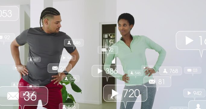 Standing couple wearing workout clothes monitoring floating social media overlays in living room