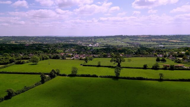 Aerial drone sideways sliding shot right to left of the village of Pilton in Somerset, with the Glastonbury Festival Pyramid Stage at centre of scene