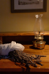 Dried lavender bouquet resting on wooden table with oil lamp