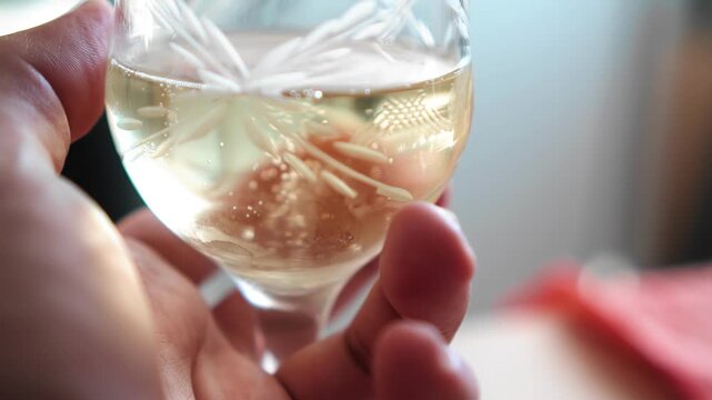 A man holds a glass of wine in his hands and turns it a little in the palm of his hand. Close-up shooting