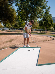 young boy playing mini golf