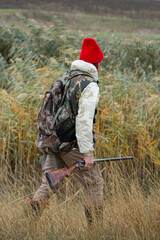 A hunter with a gun in camouflage clothing. A gentleman with a gun, medium shot, unrecognizable.