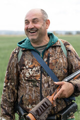 A hunter with a gun in camouflage clothing. A senior man with a gun, medium shot, searching for game.