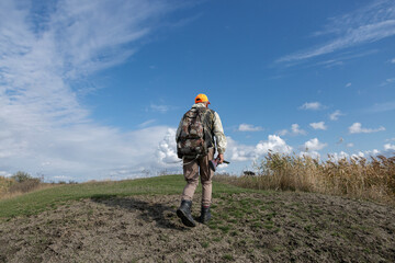 A hunter with a gun in camouflage clothing. A gentleman with a gun, medium shot, unrecognizable.